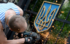 Ополченец срезает герб Украины со здания в Луганске