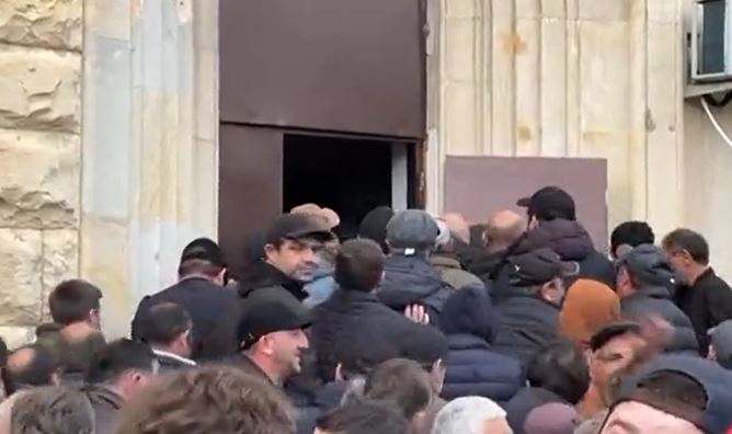 Протестующие открыли дверь в здание парламента и заходят внутрь. Стоп-кадр из видео
